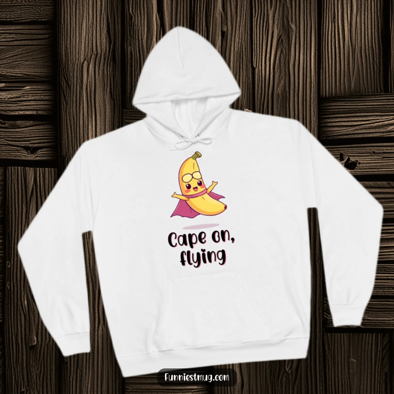 Funny hoodie depicting a mischievous banana with a cape hilariously attempting to fly, offering cozy superhero vibes.